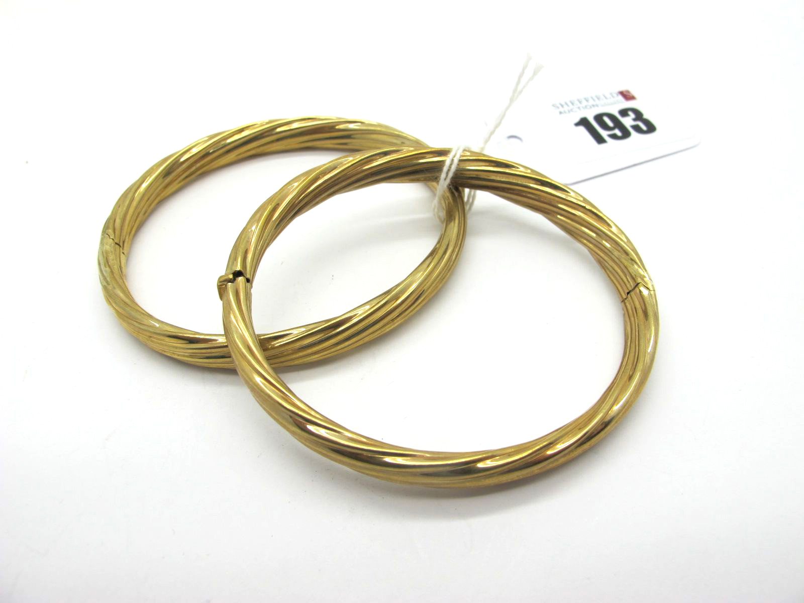 A Pair of Modern Hinged Bangles, each of twisted design, hinged to snap clasp, stamped "375" (