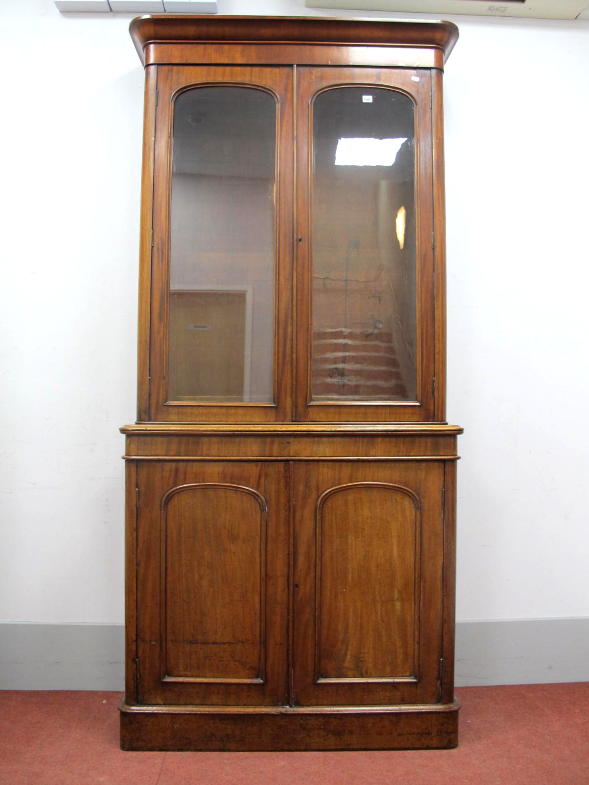 A XIX Century Mahogany Bookcase, with moulded cornice and twin glazed arched doors, the base with