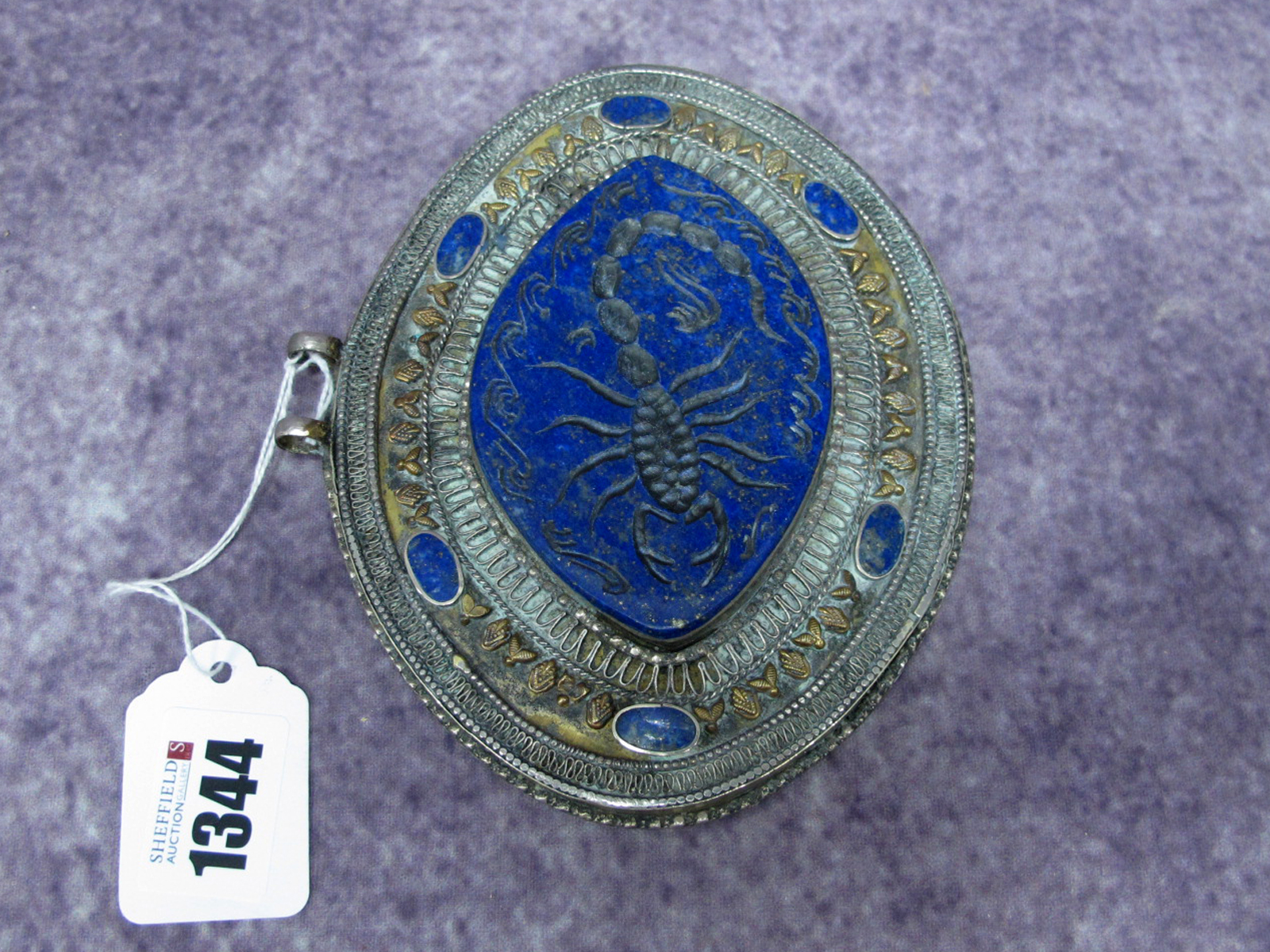 An Indian Lapis Oval Pendant, carved with a scorpion within elaborate borders and oval panels, set