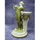 A Royal Dux Pottery Model of a Lady, standing with a cherub on her shoulder beside a tapered vase