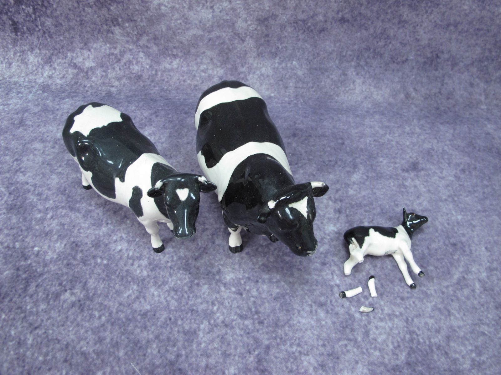 A Beswick Claybury Frisian Cow, together with (damaged) bull and calf. (3)