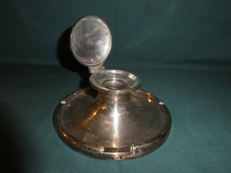 A large early 20th century silver Capstan Inkwell, circular form with hinged lid enclosing glass