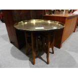 A folding hardwood Table with large brass circular top, 70cm diameter