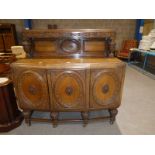 A heavy carved oak 1940's Sideboard with low back, 3 doors enclosing shelves, drawers and cellarette