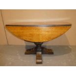 A Jacobean style oak circular drop leaf Dining Table on a central carved cup and cover support on