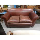 An early 20th century brown leather two seat drop arm Settee