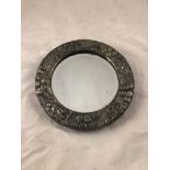 An Arts & crafts hand raised pewter bevelled circular mirror, decorated with leaf and berry