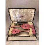 A cased set of George V hallmarked silver engine turned pink enamel dressing table furniture,