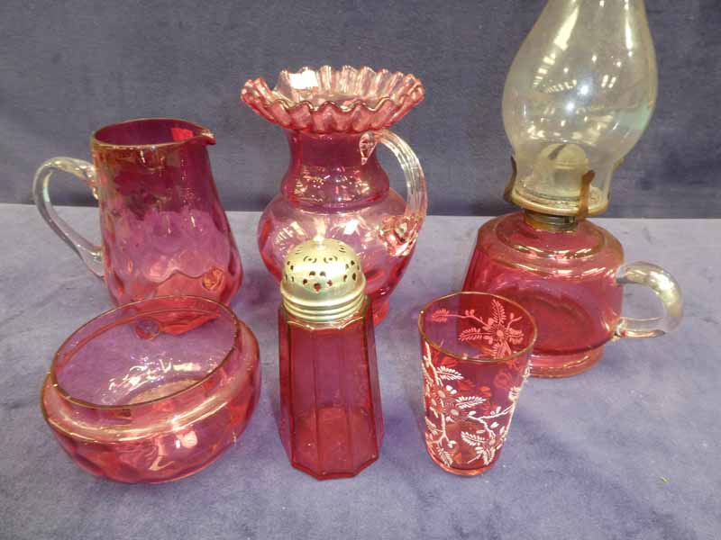 Six items of Cranberry glassware to include an oil lamp, two jugs, sugar castor, bowl and tumbler