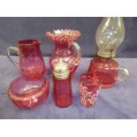 Six items of Cranberry glassware to include an oil lamp, two jugs, sugar castor, bowl and tumbler