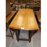 An early 20th century oak oval drop leaf dining table on twist gateleg base