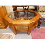 An octagonal magazine table with glass insert and caned under shelf