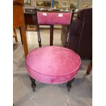 A late Victorian/Edwardian ebonised Nursing chair with pink upholstered circular seat and bar