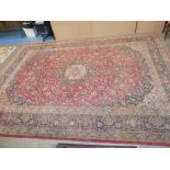 A large middle eastern style carpet, central medalion within red foliate panel and multiple