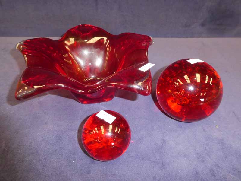 Three items of red art glass, five sided flower petal bowl and large and small paper weights with
