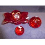 Three items of red art glass, five sided flower petal bowl and large and small paper weights with