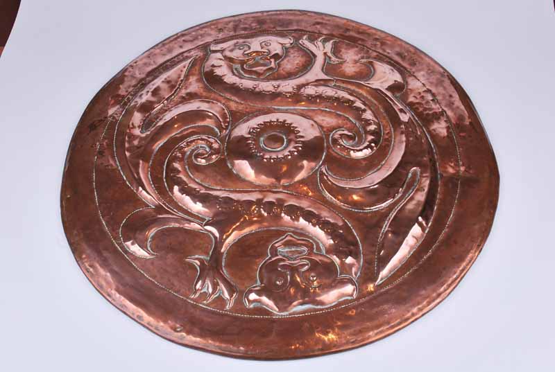 An Arts & Crafts Newlyn style circular copper charger with repoussé decoration in the form of