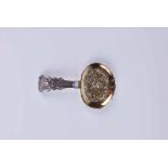A George III silver caddy spoon with repousse figural scene to the gilt bowl and rococo handle
