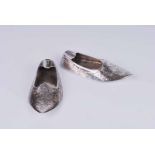 A near pair of 800 silver ashtrays in the form of eastern slippers, with differing brightcut