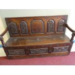 George II oak settle with berry carved panel back embellished with rosettes and early strap hinges