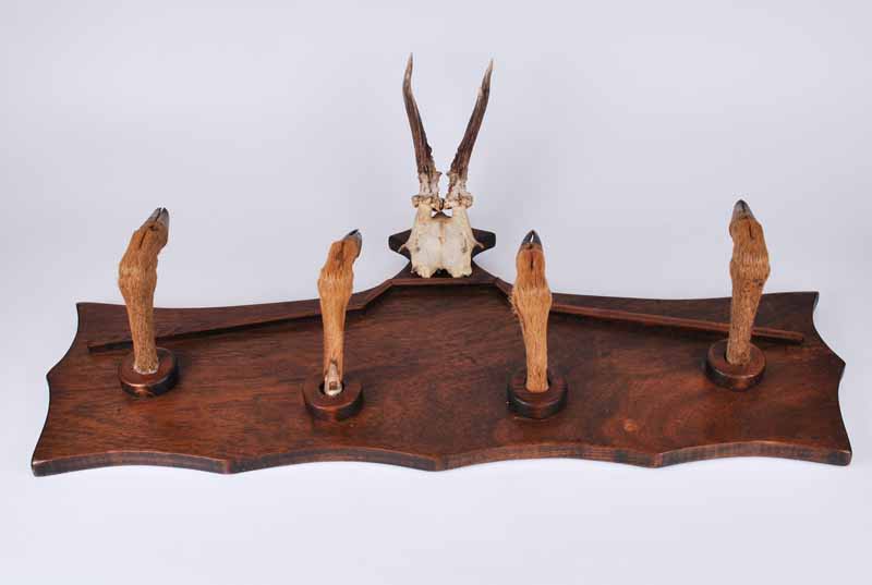 An early to mid-twentieth century wall mounted hat rack with taxidermy Roe deer slots as pegs and