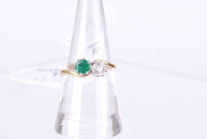 An 18 ct gold emerald and 25 point diamond cross over ring, size R, 4.2g