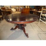 An Indonesian mahogany effect circular tilt top breakfast table