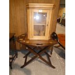 A reproduction hinged butlers tray on folding stand and a small pine display cabinet.