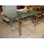 A modern glass and brushed stainless steel draw leaf table