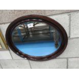 An oval mahogany framed wall mirror.