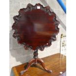 A George III style mahagony supper table, pie crust edge tilt top with shell decoration, on