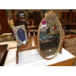 A bed table, a small oval gilt framed wall mirror and a cushioned photo frame