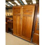 An oak two door carved and fitted double wardrobe