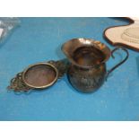 A small silver milk jug and a plated tea strainer