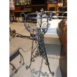 A wrought iron plant stand on triform support