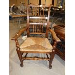 An ash rush seated Ladder back carver chair with turned stretchers and pad feet