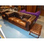 A brown leather Chesterfield three seater sofa and matching armchair and footstool