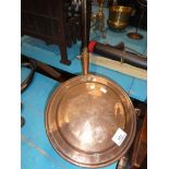 A copper bed warming pan with long handle