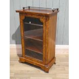 A Victorian figured walnut single door pier cabinet with brass gallery and porcelain casters