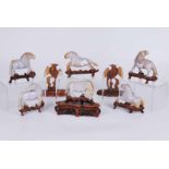 A group of early 20th century carved jade horses in celedon and russett colouration, on carved