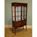 An Edward VII mahogany and marquetry inlaid display cabinet with twin glazed panel doors on splay