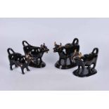 A collection of four 19th century and later black glazed Jackfield style cow creamers, three on a