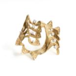 A MODERNIST DIAMOND AND 18K YELLOW GOLD BROOCH, cast as a pierced stylized waves form body mounted