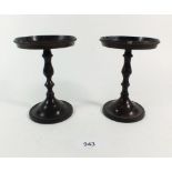 A pair of bronzed metal candle stands with turned stems, 13.5 cm tall, the tops 10cm diameter