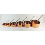 A set of six graduated copper pans with brass handles, 7cm to 16cm diameter.