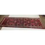 A full pile red ground Iranian runner with crossed door design, 306 x 95cm