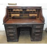 An early 20th century oak roll top twin pedestal desk with tambour front over eight drawers