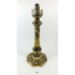 A large Art Nouveau brass based candle lamp with stylised leaf decoration, lacking glass globe