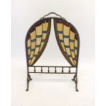 A brass Arts & Crafts stained glass firescreen with theatre curtain design, glass a/f
