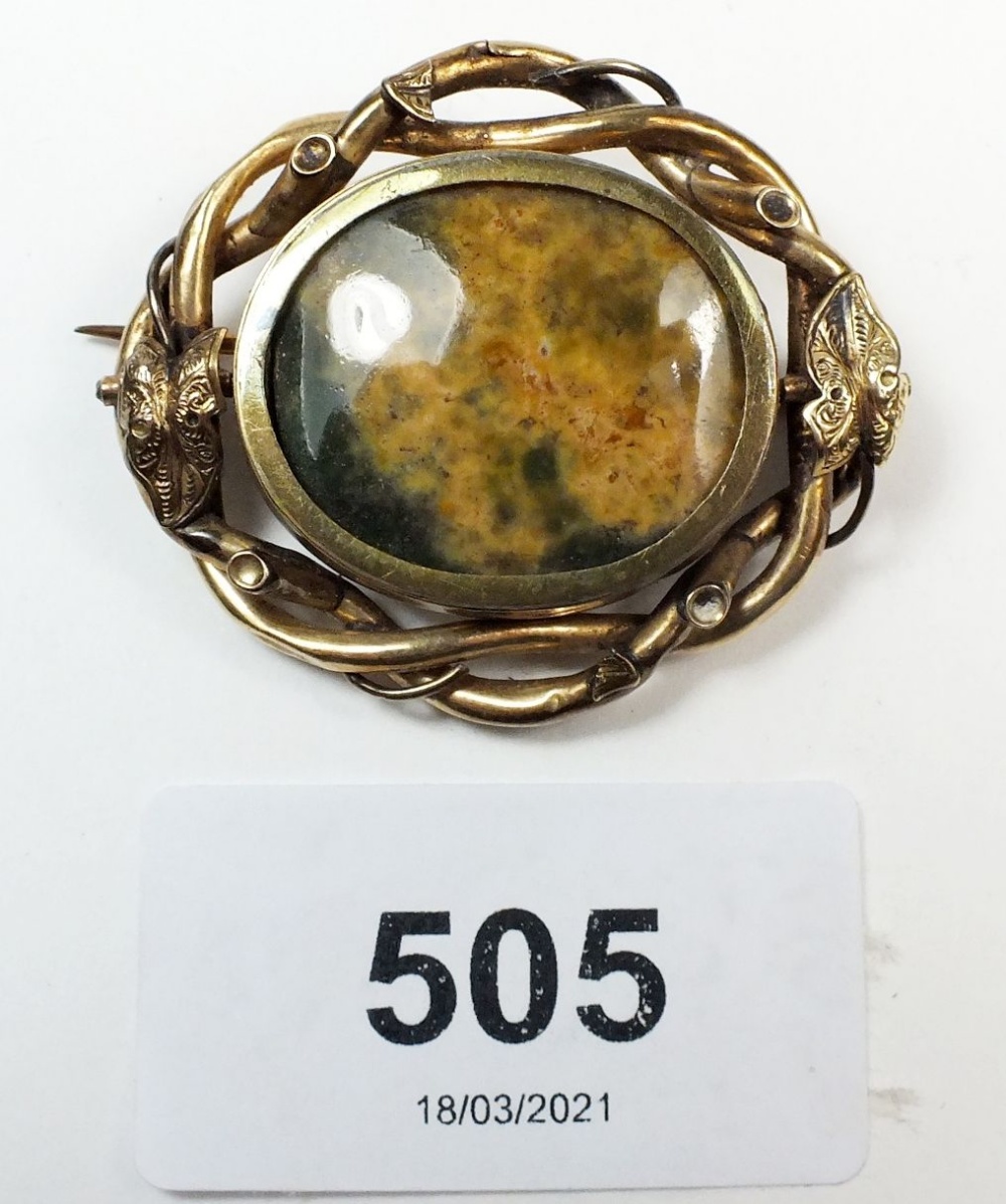 A late Georgian mourning brooch with gilt metal scroll work surround and hair locket